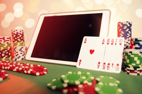 concept de poker en ligne avec une tablette, une quinte flush royale et une pile de jeton de casino